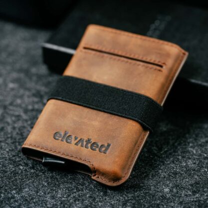Kvaliteetsest pähklipruunist Crazy Horse nahast valmistatud Elevated Extra Slim 1.0 kaarditasku kinkekarbi taustal.