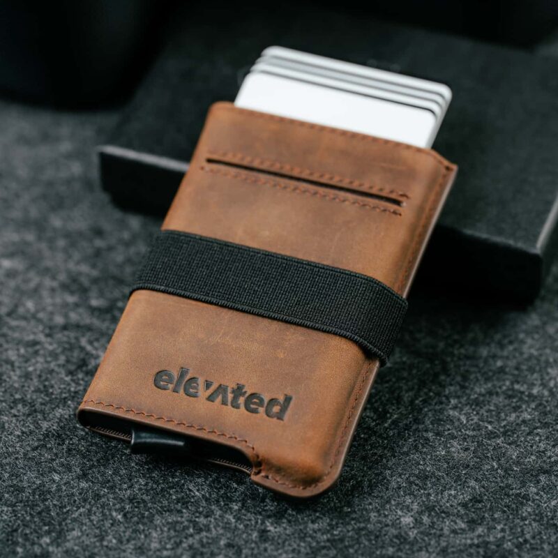 pop-up-kaarditasku-elevated-extra-slim-pruun-kaartidega Pruun Elevated Extra Slim 1.0 kaarditasku, mille pop-up mehhanism on aktiveeritud ja pangakaardid on nähtaval.
